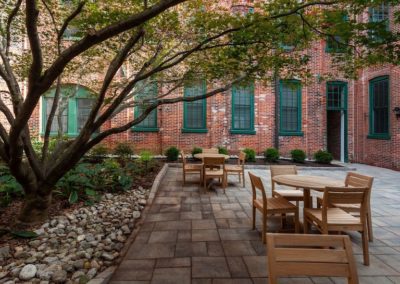 Shaded outdoor courtyard with tables and chairs at Sharples Works Apartments in West Chester, PA.
